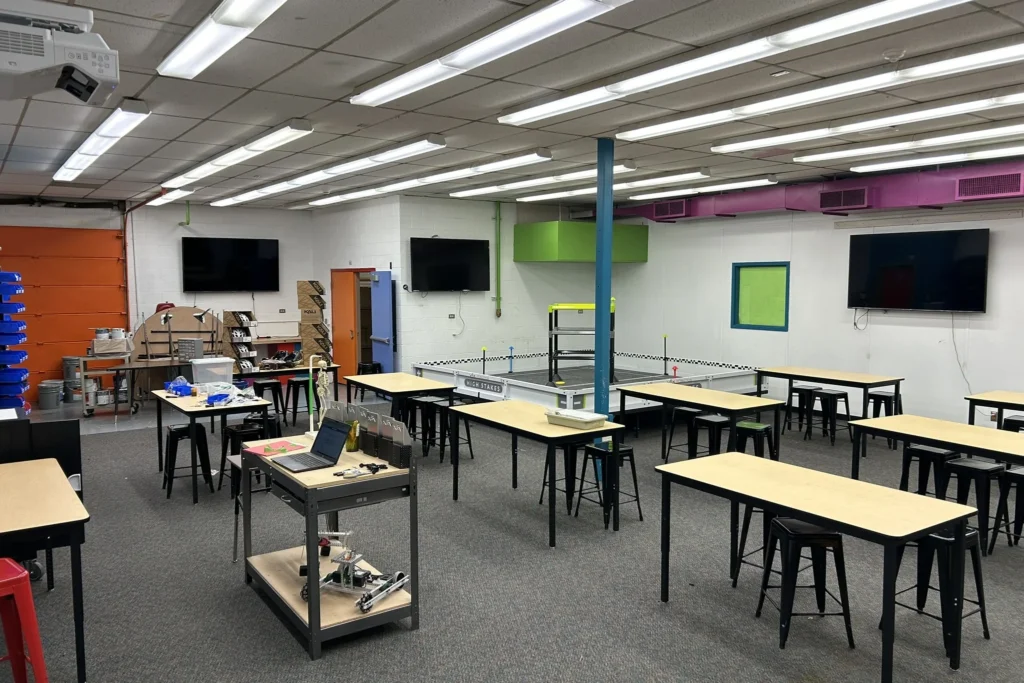 View of Sabin Middle School’s redesigned robotics lab from the entrance, teacher’s workstation and organized rows of student workbenches.